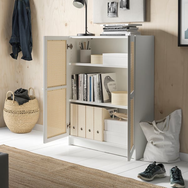Modern room with BILLY bamboo bookcase, white shelves, storing books, and a wicker basket and bag on the floor.