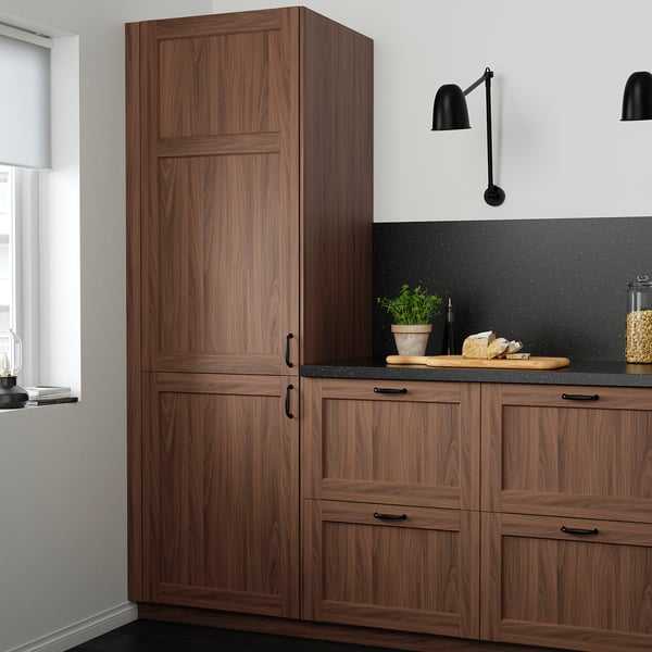 Modern kitchen featuring tall ENKÖPING walnut cabinets, sleek black countertop, and stylish lights. Tall cabinets dominate the space.