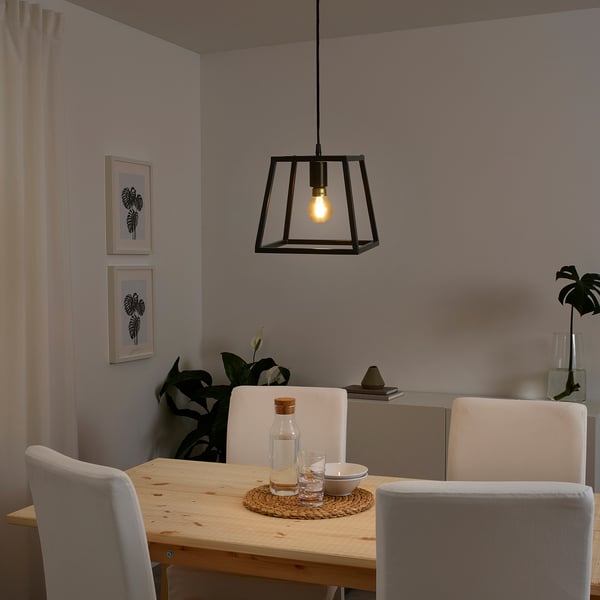 Modern dining room with FELSISK black pendant lamp over wooden table and light chairs.