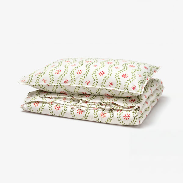 A folded FYRISVIDE duvet cover set in floral print, light beige with red and green details, made of soft cotton.