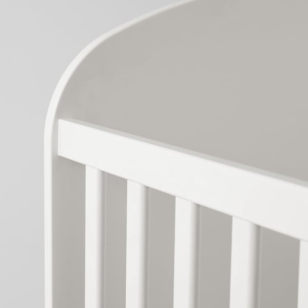 Image shows a high-quality, white, modern cot. Sleek curves, sturdy slats, and a spacious storage drawer. Perfect for a babys room.