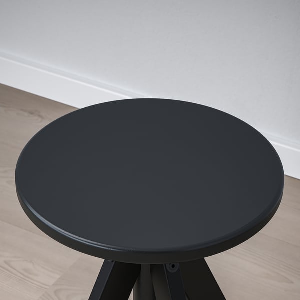 Dark wooden round table on a metal base, shown from above. Smooth, polished surface in a well-lit room.