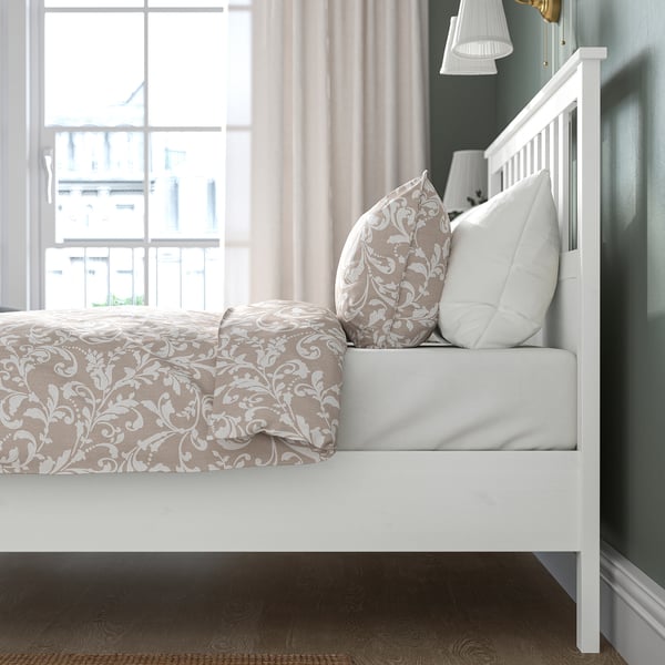 Adjustable bed with floral runner, pillows, and lamp on wooden floor.