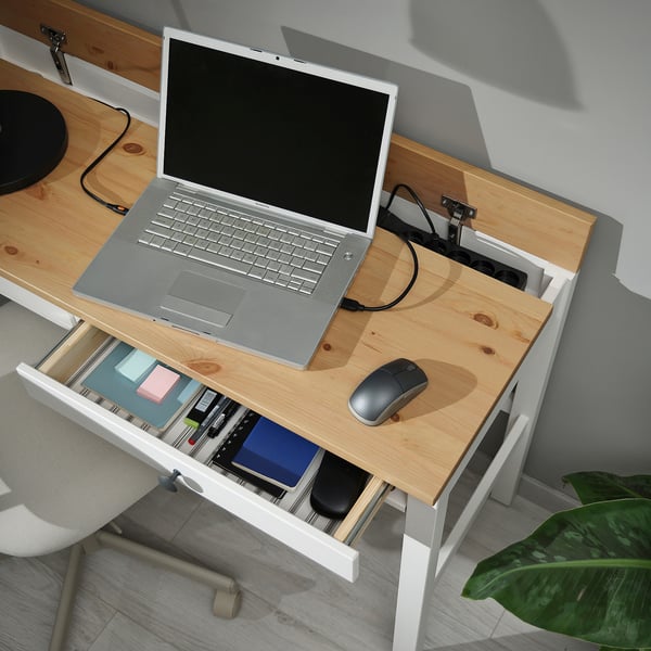 Wooden desk with laptop, mouse, and organised drawers; built-in cable management.