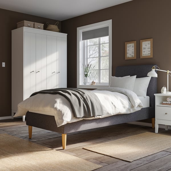 Cosy bedroom with IDANÄS grey upholstered bed, white wardrobe, wooden floor, and large window.