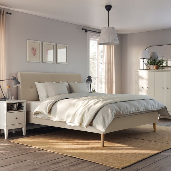 Modern bedroom with IDANÄS beige upholstered bed, wooden floor, light grey walls, white nightstands, pendant light, and wardrobe.