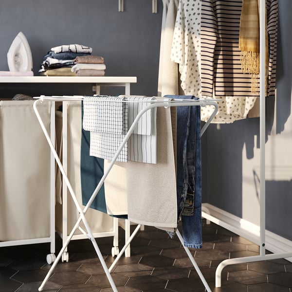 Foldable drying rack holding clothes, part of laundry setup.