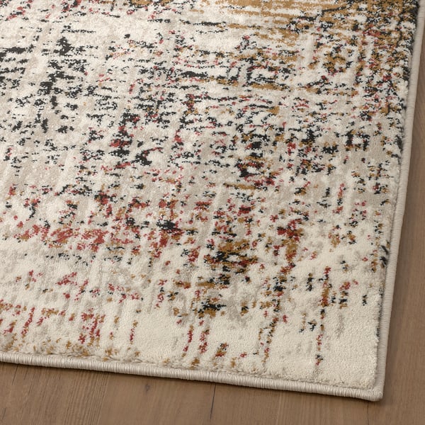Vintage-style rug on wood floor, faded colours, soft texture.