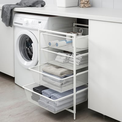 A JONAXEL white mesh storage unit next to a washing machine, holding towels and laundry supplies, ideal for small spaces.