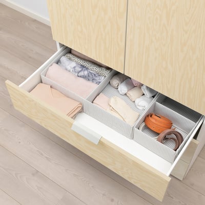 Wooden drawer organiser with compartments holding folded clothes and accessories in a neat, structured manner.