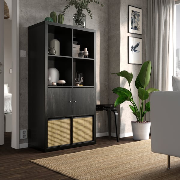 Black KALLAX shelf with vases, plants, next to white chair.