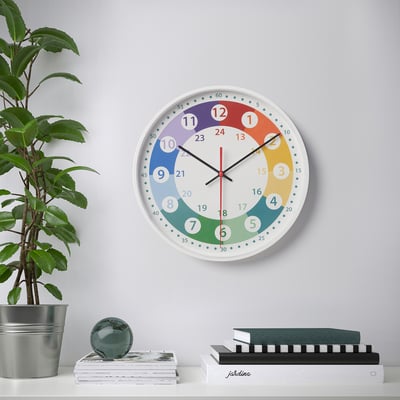 A wall clock with a colourful face showing hours, minutes, and seconds. The clock is silent and has clear, large numbers for easy reading.