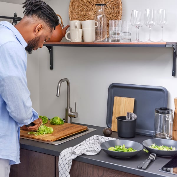 Person preps lettuce on kitchen counter with blender and salad bowl.