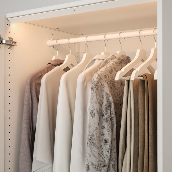 Modern closet with ÖVERSIDAN lights, organised clothes on white hangers.