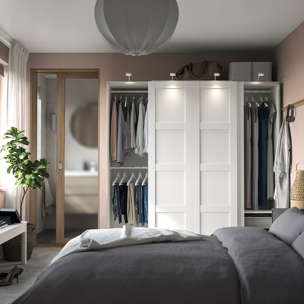 Modern bedroom with white PAX wardrobe, sliding doors, pink walls, minimalist decor.