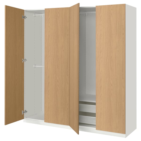An open ikea PAX wardrobe with light oak doors and white interiors, featuring shelves and a hanging rail.