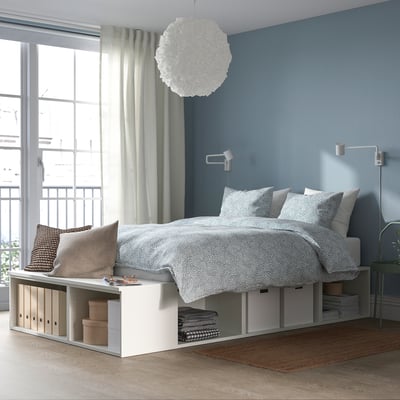 Blue bedroom with PLATSA bed, white linen, sleek decor, and storage. Large window with curtains and pendant light.