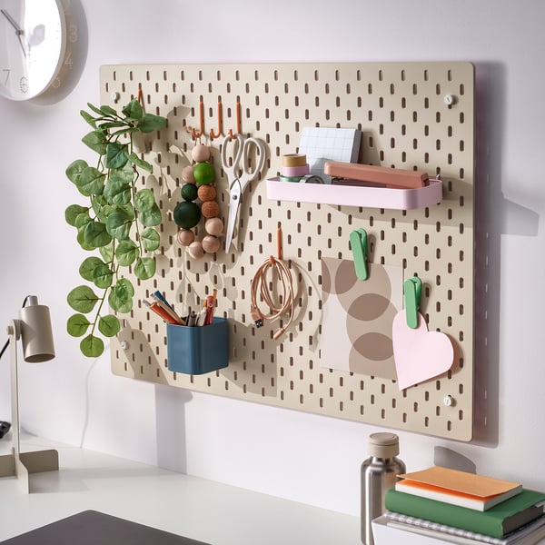 Pegboard with accessories organises desk items like scissors, pens, and small plants, keeping them neatly displayed and easily accessible.