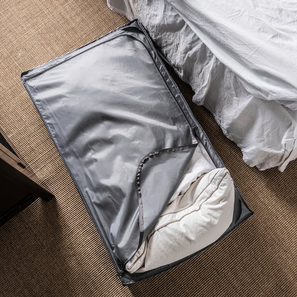 The SKUBB storage bag in grey stores bedding, with a zip and ventilation nets.