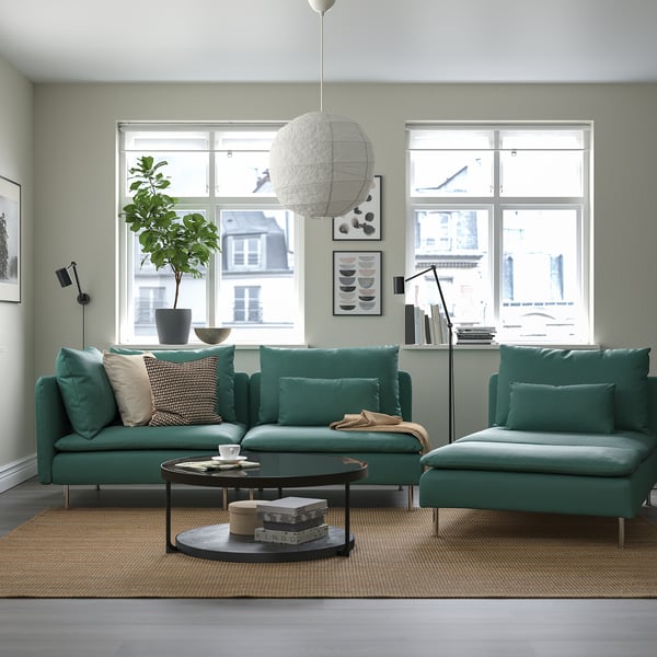 Modern living room with SÖDERHAMN green sofas, black coffee table, large windows, plant, and unique pendant light.