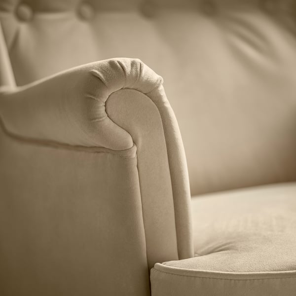 Soft, beige fabric chair with plush, rounded armrests & back, offering comfort & elegance.