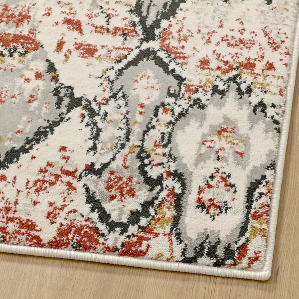 Vibrant, plush rug with intricate red floral patterns on a white background, offering durability and stain resistance.