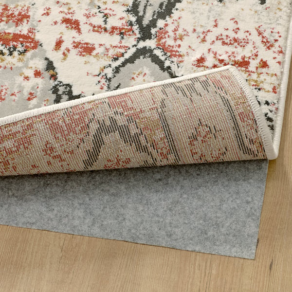 Floral rug with red accents flipped to display its durable backing.