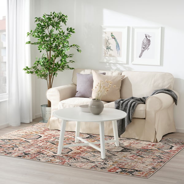 Modern living room with TOFTEBJERG rug, throw pillows, coffee table, and decor.