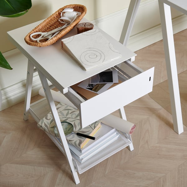 Small white TROTTEN desk with open drawer, wicker basket, book, and items inside.