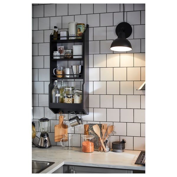 Modern kitchen with black open shelves, white tiles, marble countertop, appliances, and utensils.