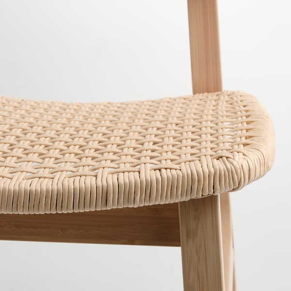 Close-up of woven chair seat: natural, tightly woven fibres over wooden frame.