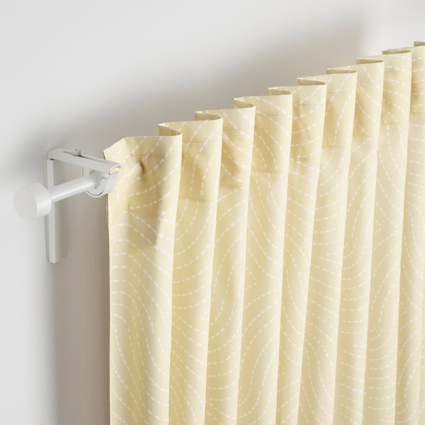 Beige curtains with white swirl patterns on a grey wall.