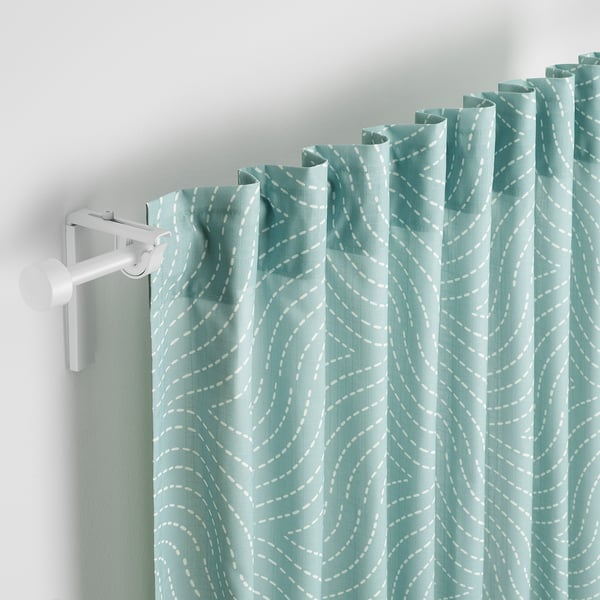 Light green curtains with wavy white patterns hang from a white curtain rod, softly filtering daylight and providing privacy.