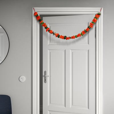 White door with colourful flower garland; hangs via string, festive decoration.