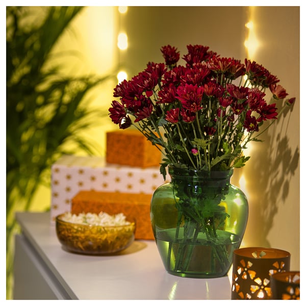 Vase with red flowers, green glass, organic shape, artwork background.