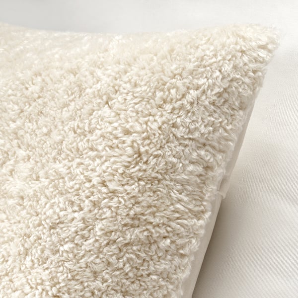 Close-up of soft, cream-colored teddy bear cushion cover with zip detail.