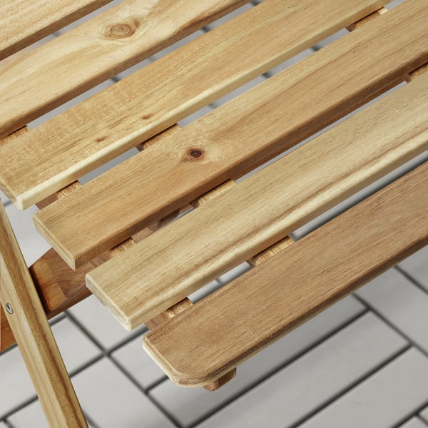Close-up of ASKHOLMEN wooden tables slatted surface. Crafted from sturdy acacia, showcasing natural wood grain and quality finish.
