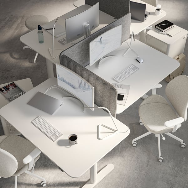 Modern white office setup: desks with screens, computers, chairs, and lamps in minimalist style.