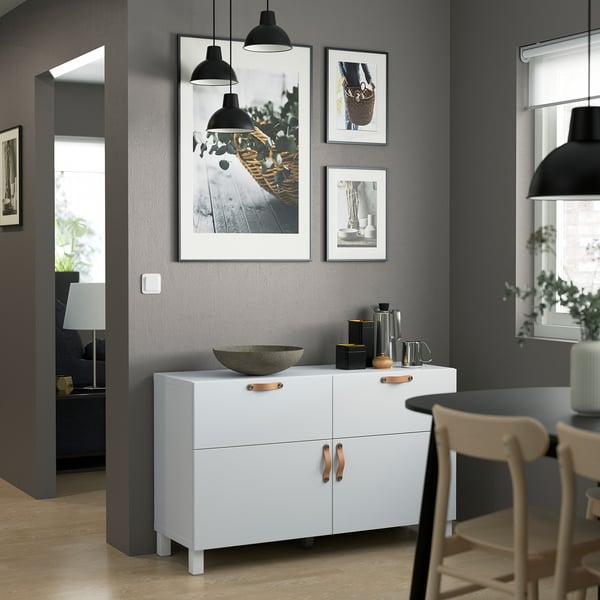Modern living room with BESTÅ unit, artwork, bowl, pendants, and wooden chair.