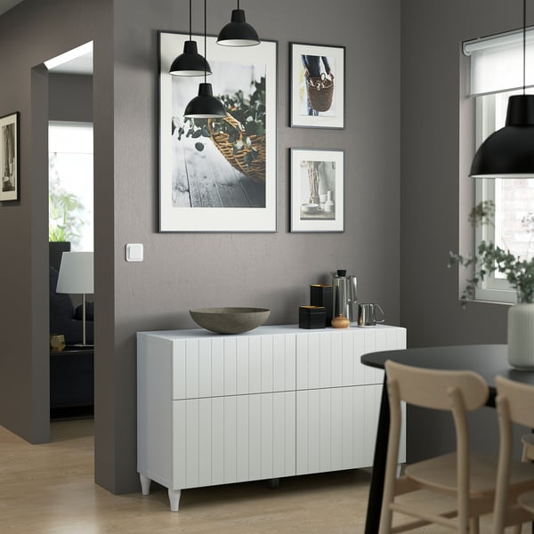 Modern living space with dark walls, featuring white sideboard, art, and dining set by light.