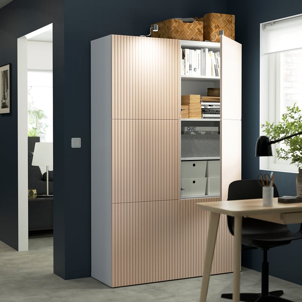 Modern storage unit with adjustable shelves, featuring soft-close hinges and a wooden finish, placed next to a desk in a home office.