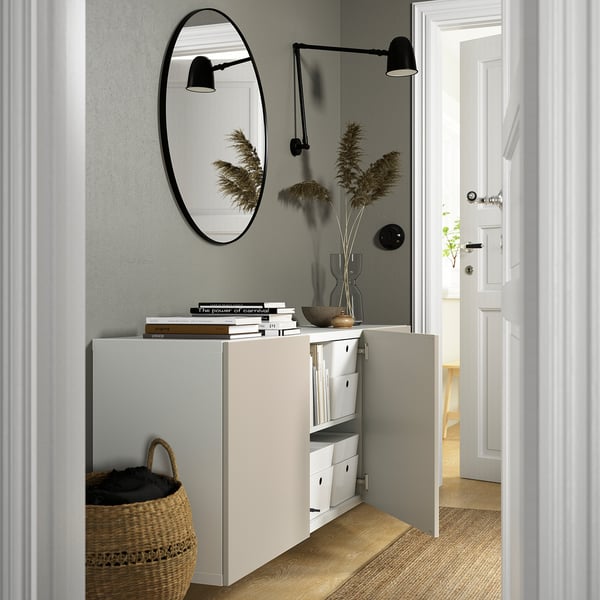 Minimalist entryway: wall-mounted storage unit with open doors, mirror, lights, and decor.