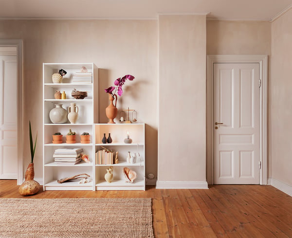 Neutral living room with white BILLY bookcases, beige walls, wooden floor, and various decorative items.