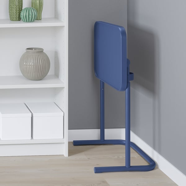 Blue laptop stand, adjustable height, tilted top, next to shelves.
