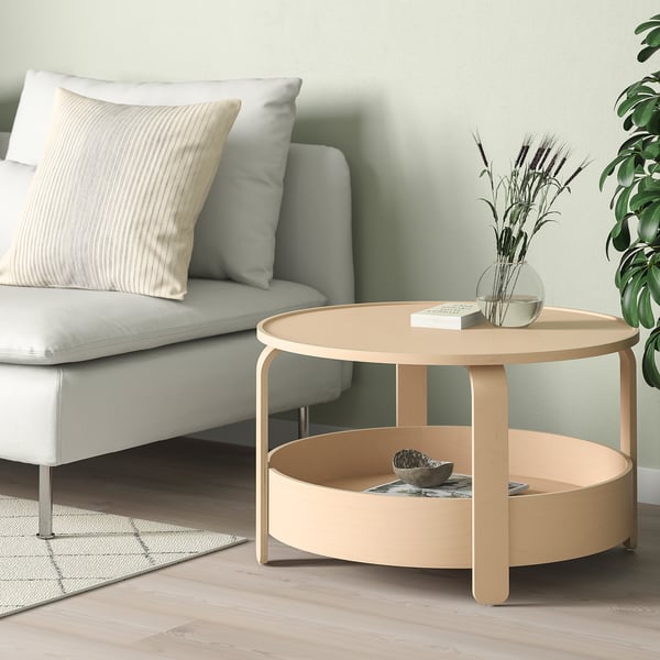 Birch veneer coffee table beside grey sofa, holding decorative items.