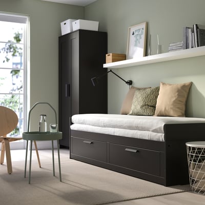 Modern bedroom with BRIMNES daybed, green walls, wardrobe, bookshelf, and wooden chair.