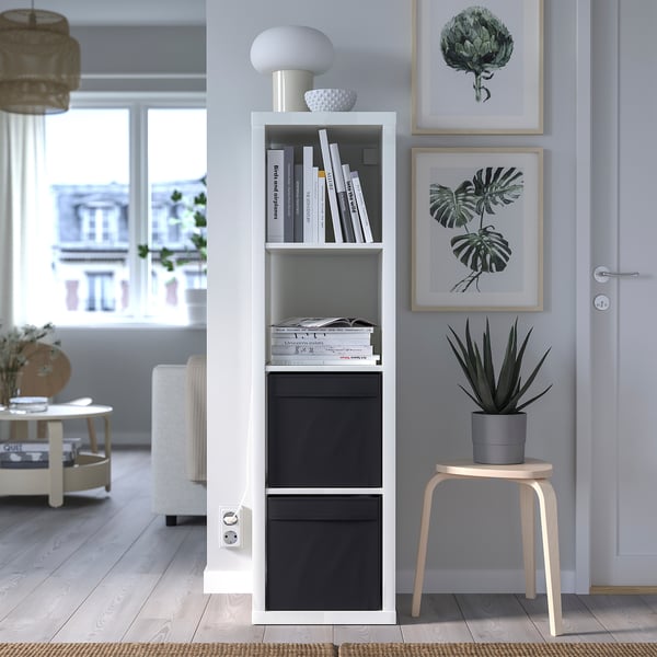 Modern living room with kallax shelving, DRÖNA boxes, lamp, and decor. Wooden stool with plant, art prints, and cosy rug by large windows.