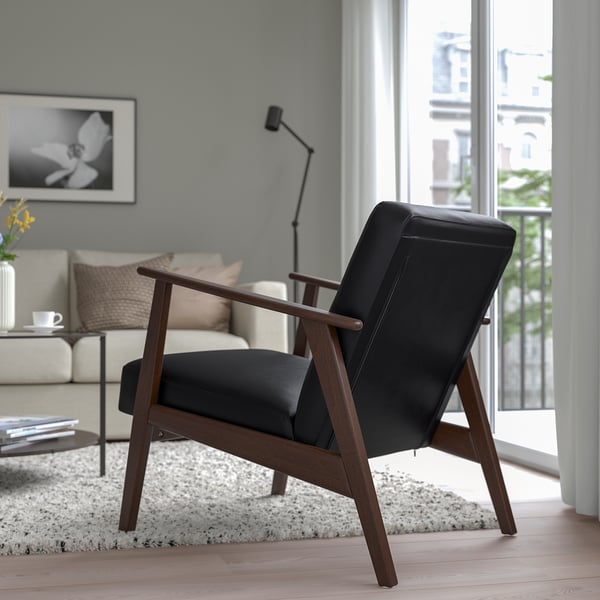 Modern living room with black EKENÄSET armchair, white sofa, coffee table, and large window.