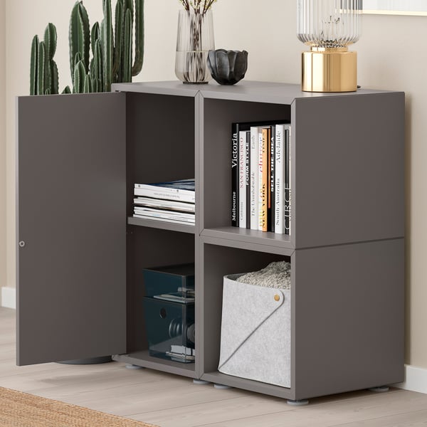 Modern grey storage unit with open shelves displaying books and a closed compartment. Adjustable shelves for versatile storage.