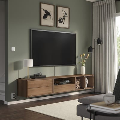 Modern living room with green walls, flat-screen tv, wooden console with decor, window with curtains, and grey chair.